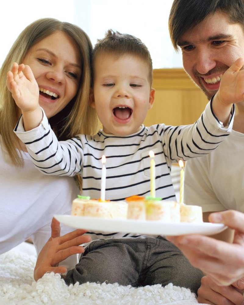 A family waves at the camera over a child's birthday cake; a LIVE mark and platform labels were added to the photo.