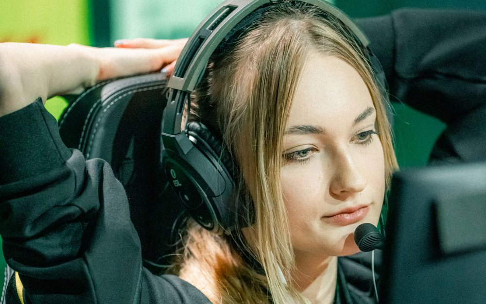 A young woman in a headset with a microphone looks at a monitor; a LIVE mark was added to the photo.