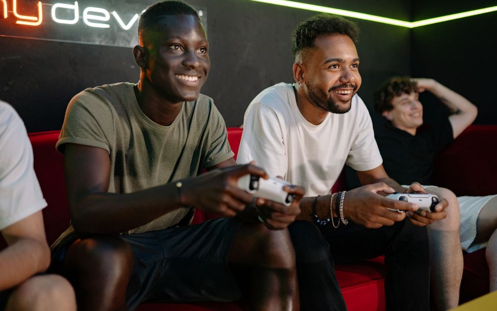 Friends on a couch laugh and play a video game together; a REC mark was added to the photo.